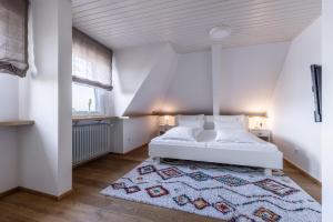 a bedroom with a white bed and a rug at Villa Neugarten in Hagnau