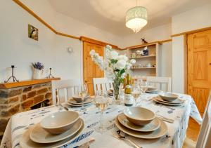 a dining room with a table with plates and glasses at Coastguard Cottage in Blagberry