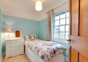 a bedroom with a bed with a dresser and a window at Coastguard Cottage in Blagberry