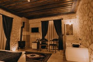 a bedroom with a bed and a tub and a table at AKRİTİS STONE HOUSE in Urgup