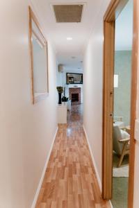 pasillo que conduce a una sala de estar con paredes blancas y suelo de madera. en The Cherry Blossom Suite, en The Patch