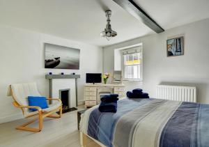 a bedroom with a bed and a chair and a television at Cockle Cottage in Appledore