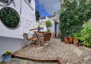 a patio with a table and chairs next to a wall at Cockle Cottage in Appledore