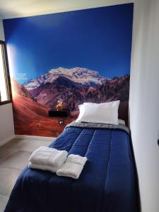 a bedroom with a blue bed with a mountain mural at 787 Suites in La Cieneguita