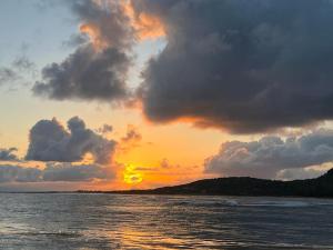 un coucher de soleil sur l'océan avec des nuages dans le ciel dans l'établissement Yeux D'azur, à Le Souffleur