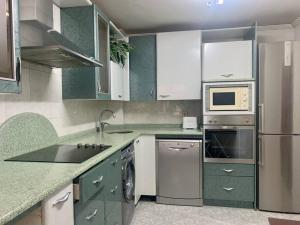 uma cozinha com armários e electrodomésticos verdes e brancos em APARTAMENTO CÉNTRICO y CÓMODO em Vitoria-Gasteiz
