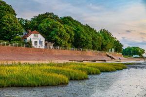 a house on the side of a river at Ferienwohnung Fresenhuus 3, FeWo Vermittlung Nordsee in Dangast +22 photos