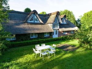 - une table et des chaises en face d'une maison au toit de chaume dans l'établissement Ferienwohnung Reethuus 6, FeWo Vermittlung Nordsee, à Dangast
