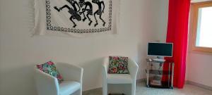 un soggiorno con 2 sedie e una TV di Appartamento Pacinotti a Cagliari