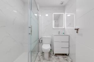 Baño blanco con aseo y lavamanos en Casa Godisa, en Torrevieja