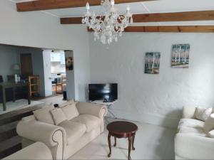un soggiorno con 2 divani e un lampadario a braccio di Blue Mountain Farm Lodge, Cabins & Cottages a Swellendam