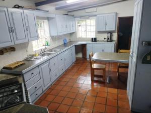 una cucina con armadi bianchi e pavimenti piastrellati di Blue Mountain Farm Lodge, Cabins & Cottages a Swellendam