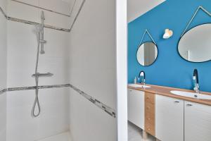 ein Badezimmer mit blauen Wänden, einem Waschbecken und einem Spiegel in der Unterkunft La Guérinière - 650m de la plage - Jardin in La Guérinière + 10 Fotos
