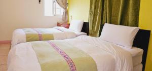 2 camas en una habitación de hotel con sábanas blancas en Auntie's Flowers Homestay, en Changbin
