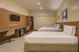 a hotel room with two beds and a tv at Rio Aeroporto Hotel Galeão in Rio de Janeiro