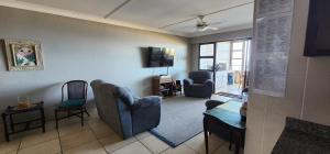 een woonkamer met een bank en stoelen en een tv bij Juanita 202 Margate North Beach in Margate