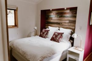 Schlafzimmer mit einem weißen Bett mit einem Kopfteil aus Holz in der Unterkunft The Mulberry Cottage in The Patch