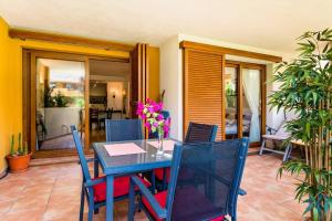 a dining room table with blue chairs and flowers on it at Amazing - La Recoletta 2 Bed apt - 2 Pools in Punta Prima