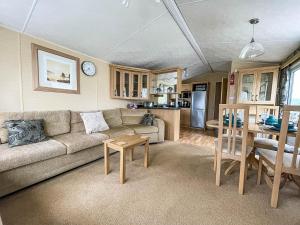 ein Wohnzimmer mit einem Sofa und einem Tisch in der Unterkunft Lovely 6 Berth Caravan With Wifi At Steeple Bay In Essex Ref 36028b in Southminster