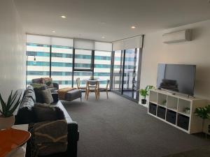 a living room with a couch and a tv and a table at Plush @ Benjamin way Belconnen in Belconnen