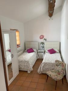 a bedroom with two beds and a mirror and a chair at New Ca de na volta - tra Liguria e Toscana in Albiano