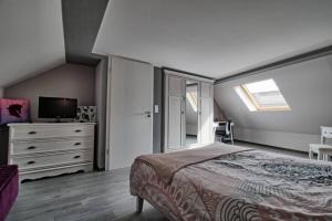 een slaapkamer met een bed, een dressoir en een televisie bij Aux grains de raisin - 6 personnes - cour privée in Scherwiller
