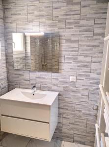 a bathroom with a sink and a tile wall at Résidence le Serra A2 in Juan-les-Pins +19 photos