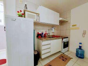 una pequeña cocina con armarios blancos y microondas en Apto. 1 dormitório no M. de Nassau - Ed. Manhattan Home Service 302, en Caruaru
