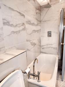 un bagno bianco con vasca e lavandino di Chelsea Flat 10 mins Harrods, Balcony, Gym, Air Conditioning a Londra