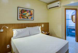 um quarto com uma cama branca e uma janela em Rio Aeroporto Hotel Galeão no Rio de Janeiro