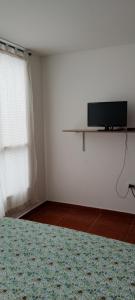 a bedroom with a tv on a white wall at Dulce hogar baño compartido in Chía