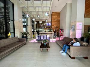 a woman sitting on a couch in a lobby at Coruja Imob - Flat Crystal Place in Goiânia