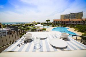 einen Tisch mit Tellern und Gläsern auf einem Balkon mit Pool in der Unterkunft Residence Porto Sole in Cavallino-Treporti