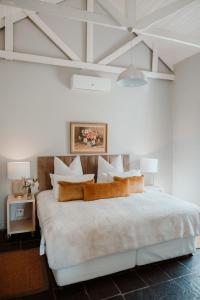 a white bedroom with a large white bed with pillows at Saronsberg Vineyard Cottages in Tulbagh