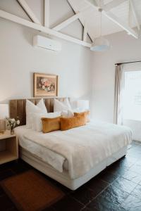 a white bedroom with a large white bed with pillows at Saronsberg Vineyard Cottages in Tulbagh
