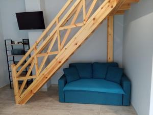 a living room with a blue couch under the stairs at Xristos apartment and maisonettes in Sykia Chalkidikis