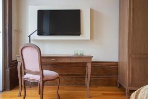 um quarto com uma cadeira e uma televisão na parede em Dom José Alojamentos by Guestify em Guimarães