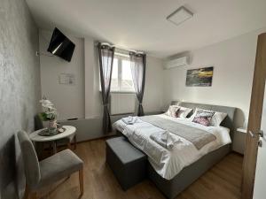 a bedroom with a large bed and a chair at San Lux Dunavska in Novi Sad