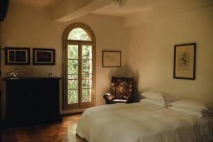 1 dormitorio con cama, ventana y silla en Le dimore de Il borgo del balsamico, en Albinea