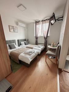 a bedroom with two beds and a table at San Lux Dunavska in Novi Sad