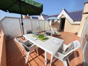 een witte tafel en stoelen op een balkon met een parasol bij Apartamentos Playa San Juan Tenerife in Playa de San Juan