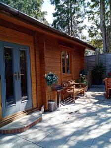 a wooden cabin with a bench and a door at tranquil log cabin in Shepton Mallet
