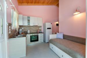 a small kitchen with pink walls and white cabinets at Kabos house in Mastorátika +6 photos