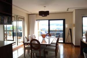 a dining room with a table and chairs and windows at Casa Primavera by The Lodges in Campos do Jordão