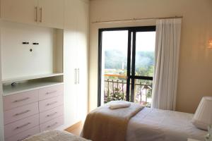 a bedroom with a bed and a large window at Casa Primavera by The Lodges in Campos do Jordão