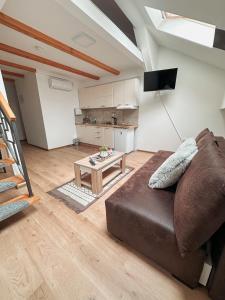 a living room with a brown couch and a table at San Lux Dunavska in Novi Sad