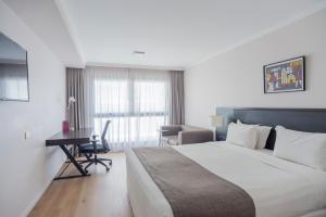 a hotel room with a large bed and a desk at After Hotel Montevideo in Montevideo