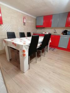 a kitchen with a table with chairs and red cabinets at Cantinho da Familia in Avis