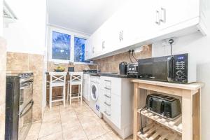 a kitchen with white cabinets and a microwave at Buckland court in London