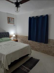 a bedroom with a bed and a blue curtain at CASA EM PRAIA SECA in Araruama